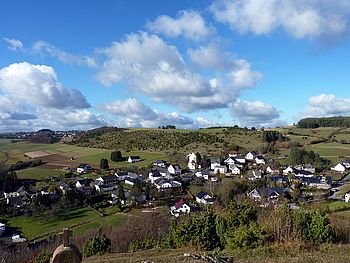 Dorf in Hügellandschaft mit blauem Himmel
